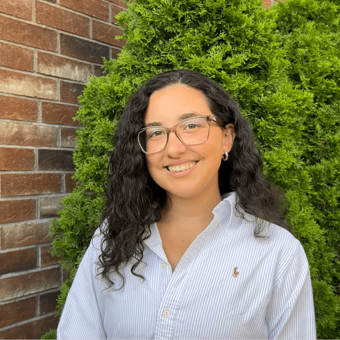 A woman standing in front of a brick wall.